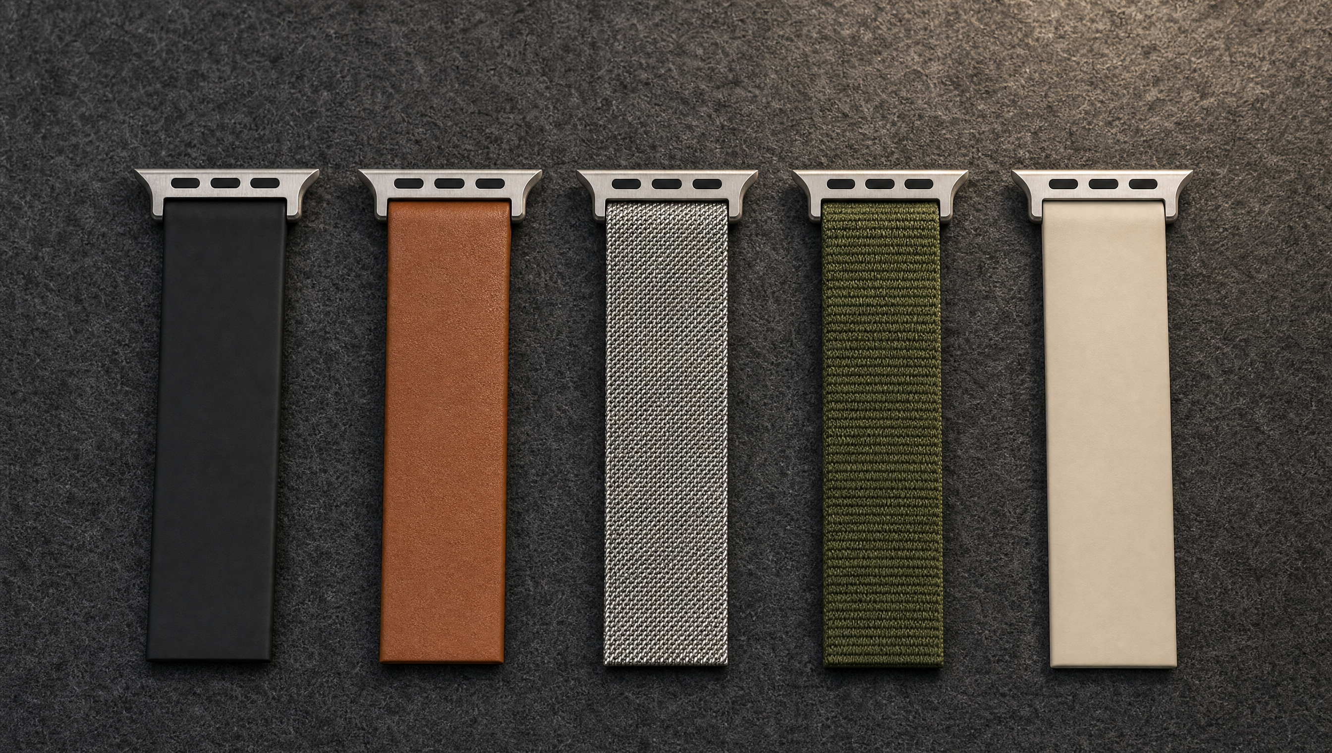 Fünf Armbandabschnitte nebeneinander auf dunklem Filz: schwarzes Silikon, braunes Leder, Edelstahlgeflecht, olivgrünes Nylon und sandfarbenes Silikon, jeweils mit Anschlussstück. Mit KI erstellte Materialdarstellung.